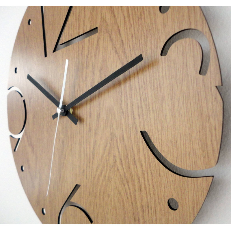 Ceas rotund din lemn cu numere sculptate 3, 6, 9 și 12 pe o bază din stejar deschis la culoare.